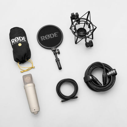 Silver RØDE NT1 5th Generation microphone laid out with a dust cover, pop filter, shock mount, USB-C cable and XLR cable