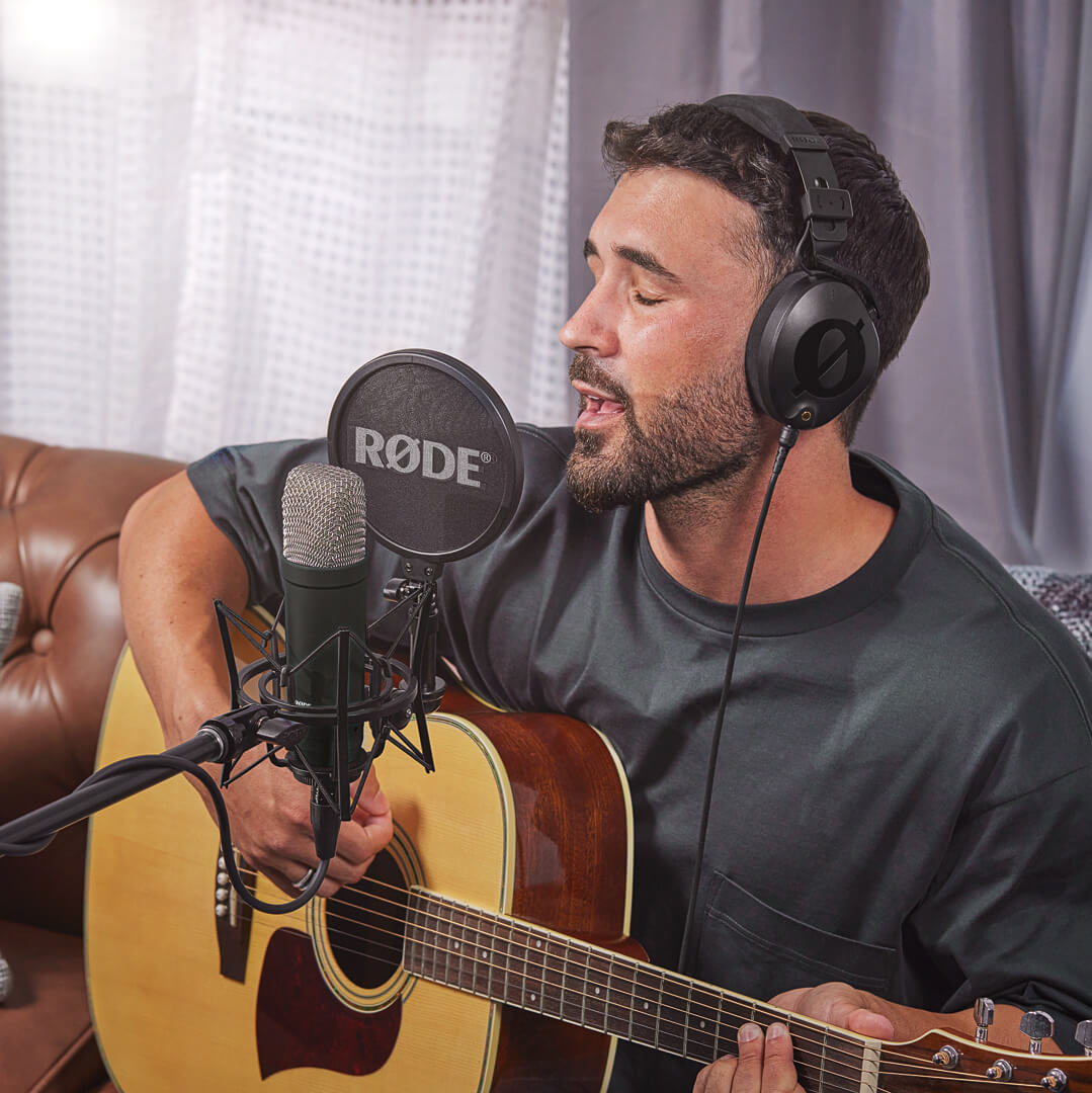 Musician recording acoustic guitar and vocals with the black RØDE NT1 Signature Series